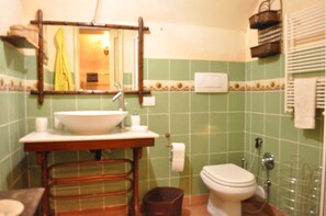 Casa de banho com lavatório, espelho, sanita e um pequeno contentor de lixo.