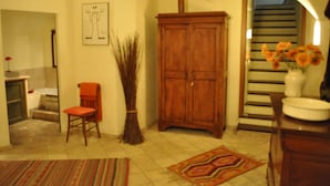 A bathroom with a wooden cabinet, a chair, a vase with flowers, and a patterned rug. - A Gorgeous Large Flat in Trastevere with a Beautiful Terrace (Roma)
