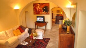 A living room with a white sofa, a red rug, a television, and a painting on the wall. - A Gorgeous Large Flat in Trastevere with a Beautiful Terrace (Roma)