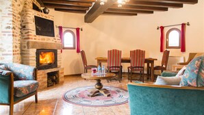 A cozy living room with a stone fireplace, striped chairs, and a round coffee table. - Holiday home " la tour 2 étoiles "Normandie (Saint-Étienne-Sous-Bailleul)