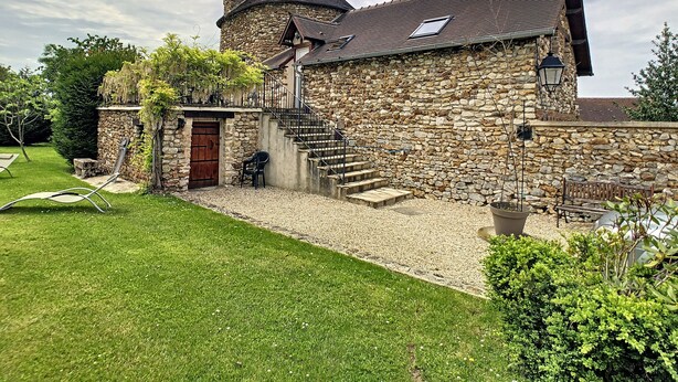 A stone house with a wooden door, a staircase, and a small garden area with a lawn and a bench. - Holiday home " la tour 2 étoiles "Normandie (Saint-Étienne-Sous-Bailleul)