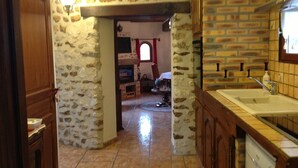 A kitchen with stone walls, a wooden door, and a tiled floor. - Holiday home " la tour 2 étoiles "Normandie (Saint-Étienne-Sous-Bailleul)