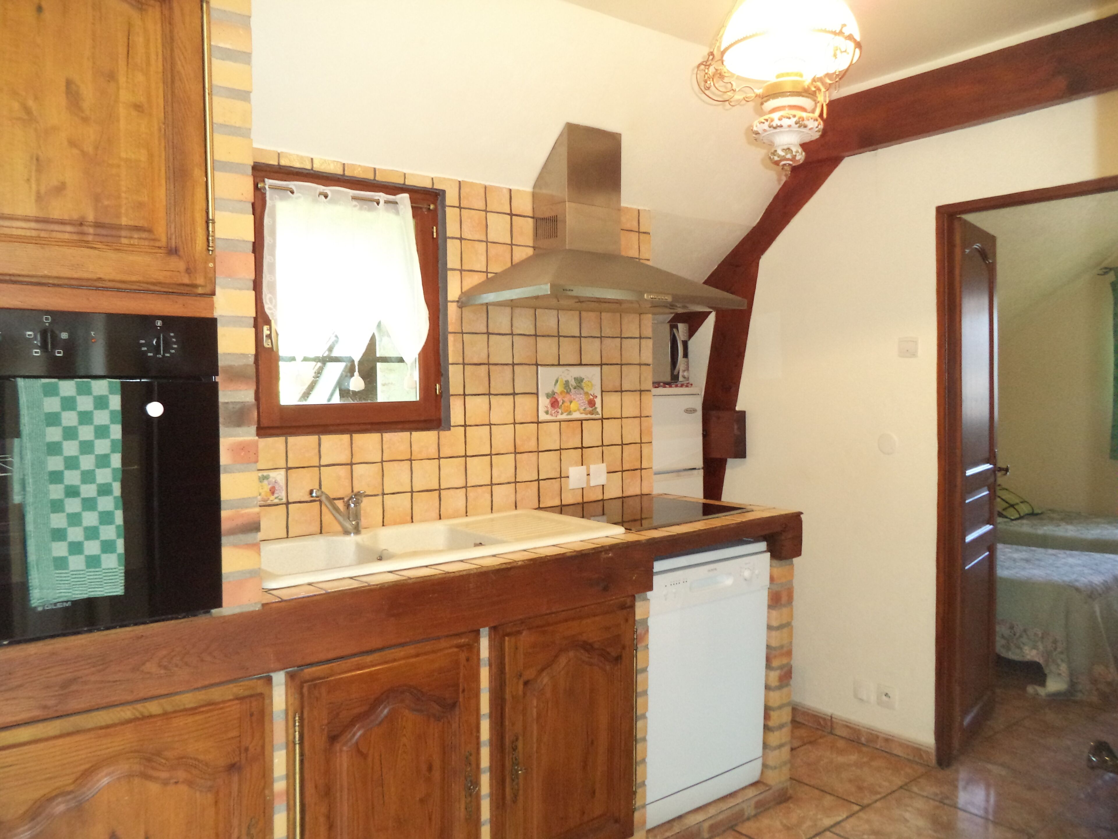 Una cocina con armarios de madera, un refrigerador negro, un lavavajillas blanco y salpicadero de azulejos.