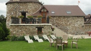 A stone building with a round tower, a staircase, and outdoor seating. - Holiday home " la tour 2 étoiles "Normandie (Saint-Étienne-Sous-Bailleul)