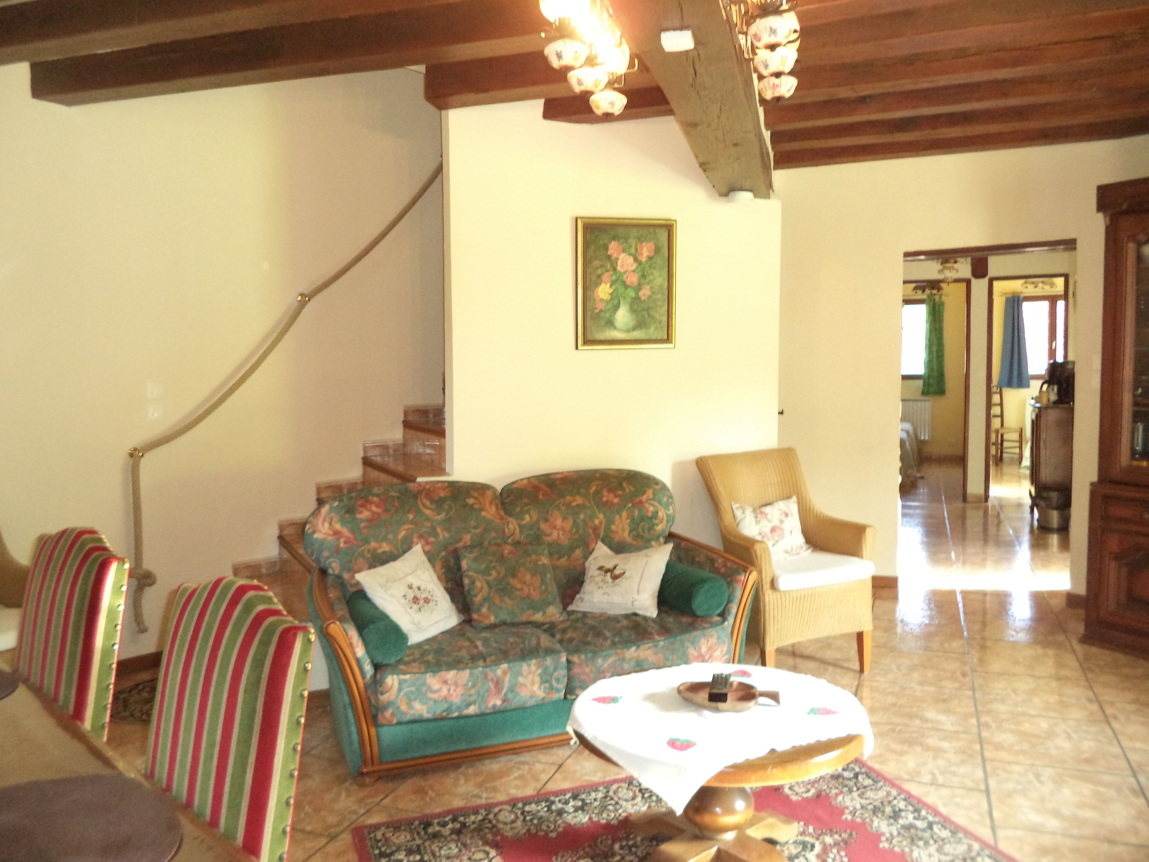 Un salon avec un canapé, des fauteuils, une petite table et un escalier.