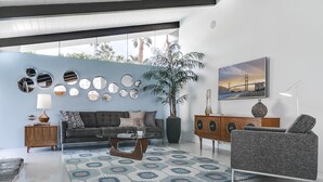 A modern living room with a sofa, coffee table, and decorative mirrors on the wall. - LOVE ... and MISCHIEF in Historic Twin Palms (Palm Springs)