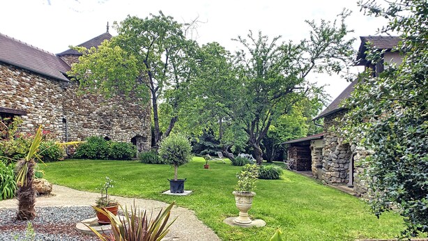 Un bâtiment en pierre avec une pelouse bien entretenue et des plantes en pot.