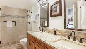 Une salle de bain comprenant une douche, des toilettes, un meuble-lavabo et deux miroirs.