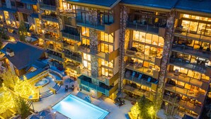A multi-story hotel with outdoor swimming pool, sun loungers, and a fire pit area.
