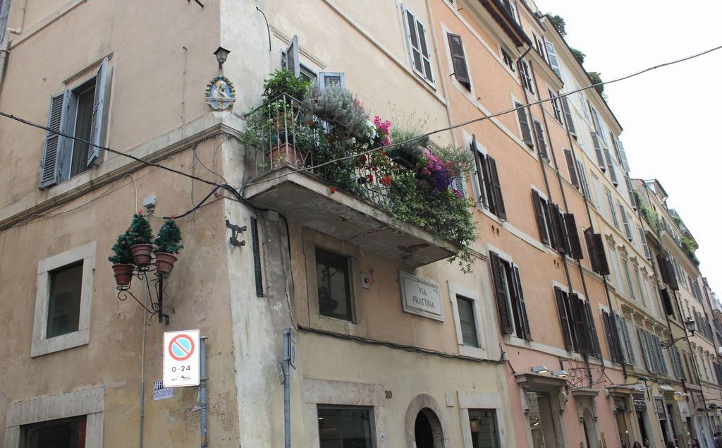 Un bâtiment doté d’un balcon agrémenté de fleurs et de plantes en pot.