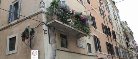 A building with a balcony adorned with flowers and potted plants.
