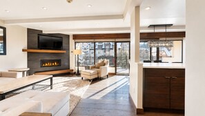 Una sala de estar moderna con chimenea, sofá y televisor montado en la pared.