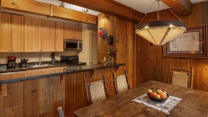 A rustic kitchen with wooden cabinets, a stainless steel microwave, and a dining table with chairs. - Vantage Point 115 - 2 Bedroom Gold (Circle Vail)