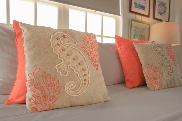 Drift to sleep in Kas di Amor’s oceanview bedroom, where a queen sleigh bed and local art set a serene scene. Wake to sunrise colors and sailboats just beyond your window.