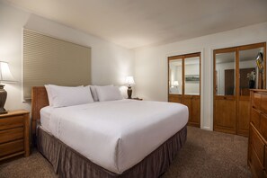 A hotel room with a large bed, wooden nightstands, a window with blinds, a wardrobe, and a television. - Enzian 115 - Lionshead Vail 3BR, Minutes to Gondola + Valley Views (Vail)