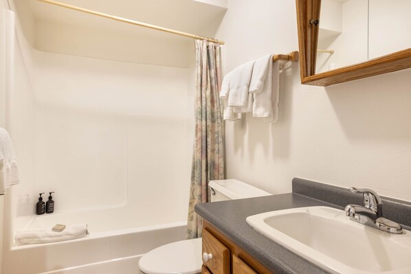 A bathroom with a bathtub, toilet, and sink.