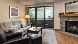 Un salon doté d’une cheminée, d’un canapé, d’une table basse et offrant une vue sur l’extérieur grâce à une porte-fenêtre coulissante.