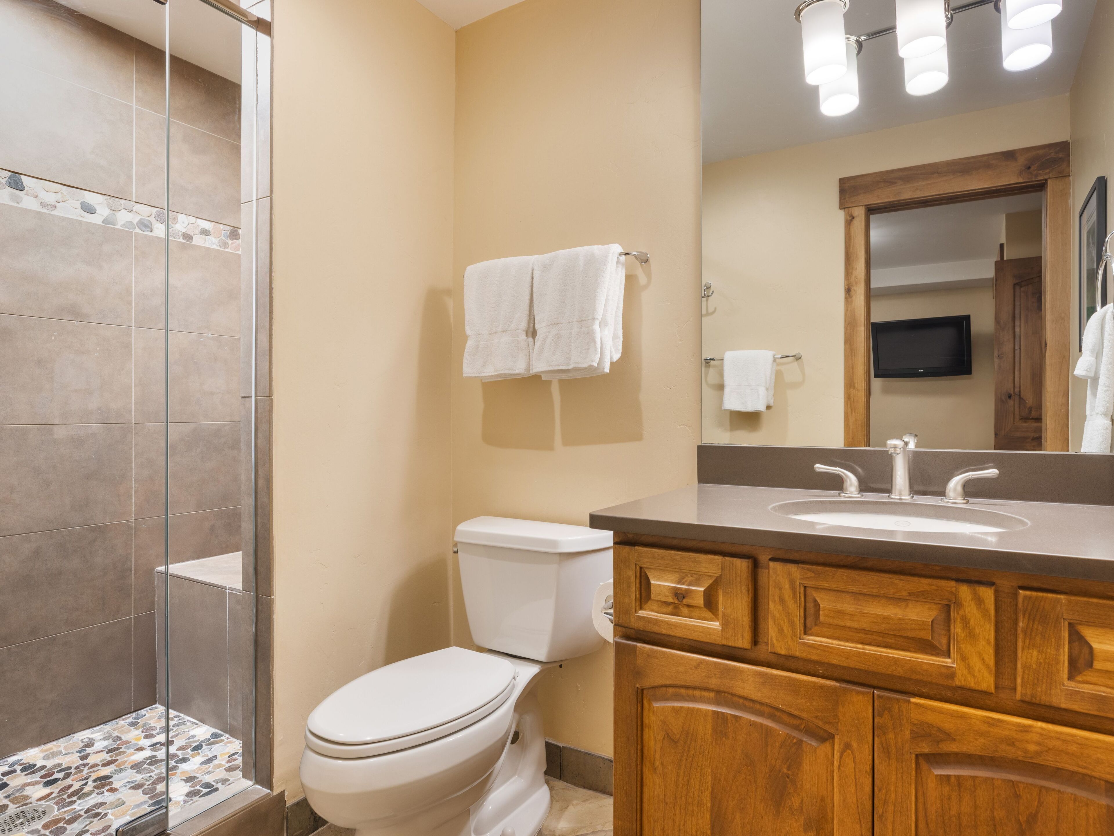 A bathroom with a toilet, sink, and wooden vanity.