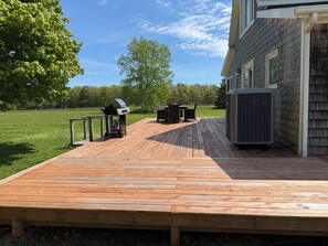 A wooden deck with outdoor furniture, a grill, and an air conditioning unit.