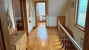 A spacious hallway with wooden flooring, a staircase, and a window providing natural light. - Large Century Home with Vineyard. Very private with a grand ocean view.  (Lot 63)
