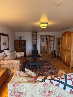A living room with a sofa, a table, a fireplace, and wooden furniture. - Large Century Home with Vineyard. Very private with a grand ocean view.  (Lot 63)