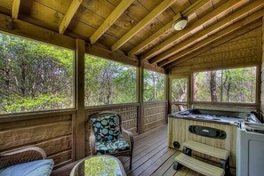 Relax on the deck with a hot tub and comfortable seating, surrounded by the serene forest view.