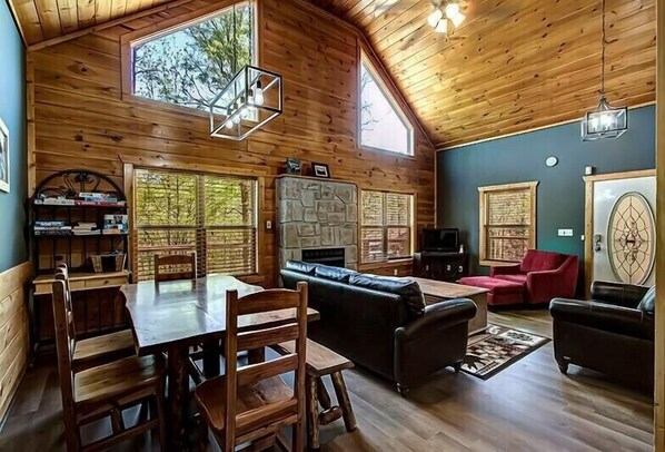 Cozy cabin-style room with a dining table, sofa, and fireplace, perfect for relaxing and enjoying the views.