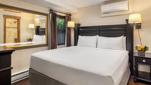 A hotel room with a large bed, a mirror, an air conditioning unit, and a nightstand with a lamp and flowers. - Landmark 111 - 1 Bedroom Platinum (Vail)