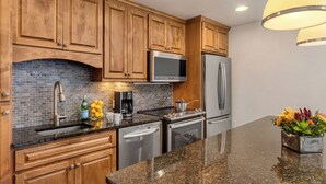A kitchen with wooden cabinets, a granite countertop, stainless steel appliances, and a backsplash. - Landmark 111 - 1 Bedroom Platinum (Vail)