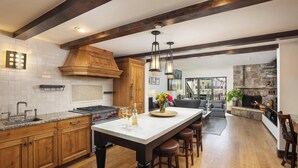 A spacious kitchen with wooden cabinets, a large island, and a stone fireplace.