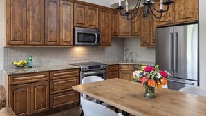 A kitchen with wooden cabinets, a stainless steel refrigerator, a microwave, and a stove. - Landmark 220 - 3 Bedroom Platinum (Vail)