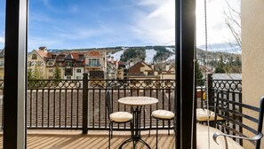 A balcony with a table and chairs, a view of a town with buildings and a snowy landscape. - Landmark 208 - 3 Bedroom Platinum (Vail)