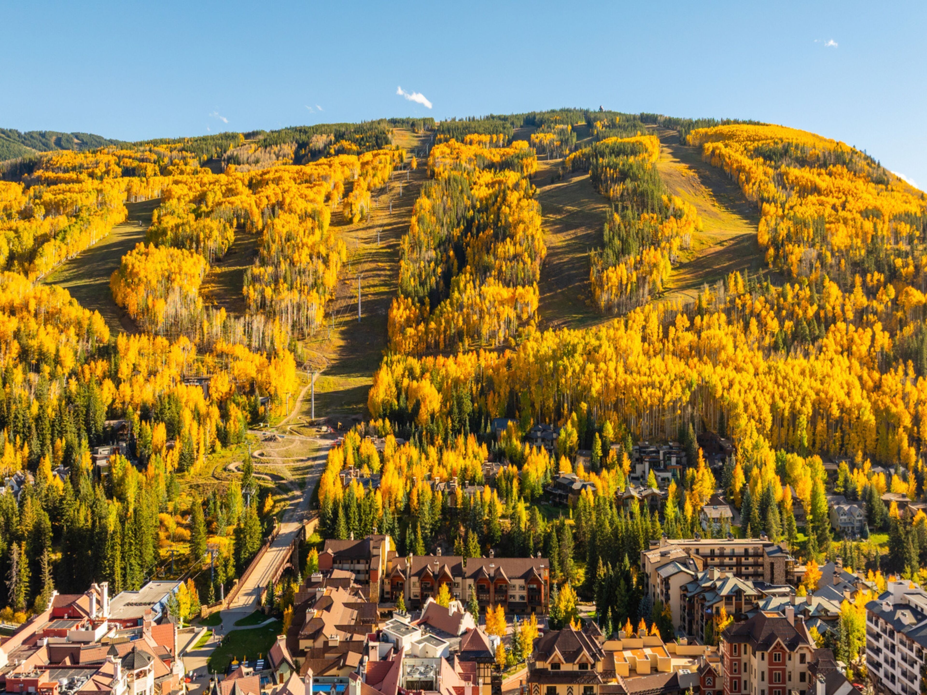 A town nestled in a valley with autumnal trees and a mix of traditional and modern architecture.