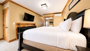 A bedroom with a large bed, a flat-screen TV mounted on the wall, a wooden headboard, and a ceiling light fixture. - Landmark 208 - 3 Bedroom Platinum (Vail)