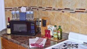A kitchen counter with a microwave, bottles of water, a wine bottle, and condiments. - CORNER OF CALM IN THE ♥ OF CEDAR RAPIDS! (Cedar Rapids)