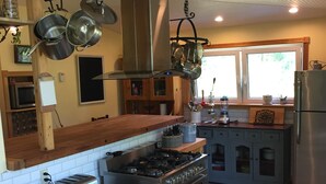 Cozinha moderna com eletrodomésticos de aço inoxidável, armários de madeira e uma janela grande que oferece muita luz natural.