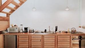 A kitchen with wooden cabinets, a microwave, toaster, kettle, and various kitchen utensils. - Cosy maisonette in a beautiful garden - historic ambience and modern comfort (Quito)