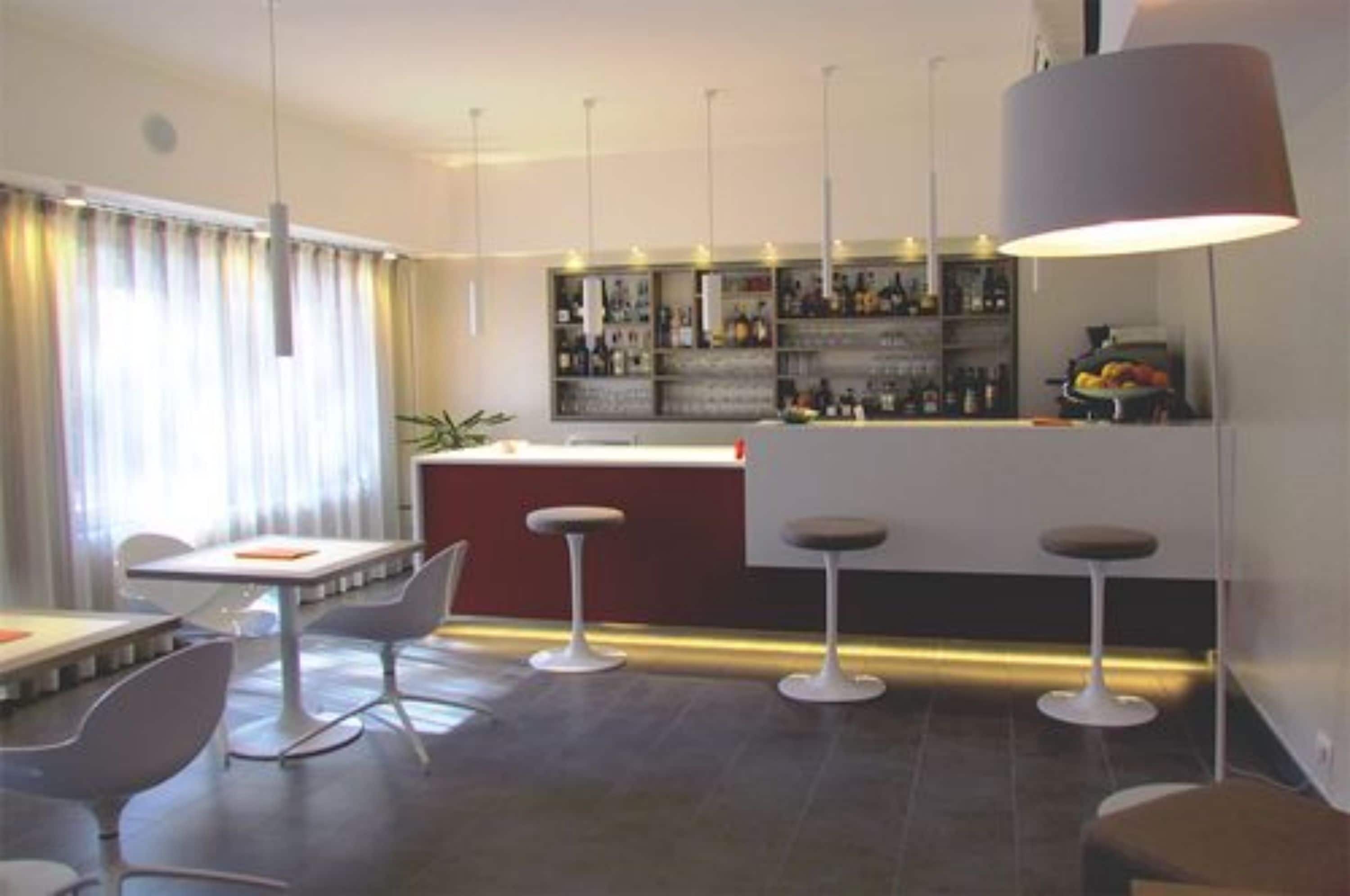 A modern bar area with a bar counter, stools, and hanging pendant lights.