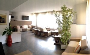 A modern living room with a sofa set, a coffee table, and a large potted plant. - Hotel Palme (Monterosso al Mare)