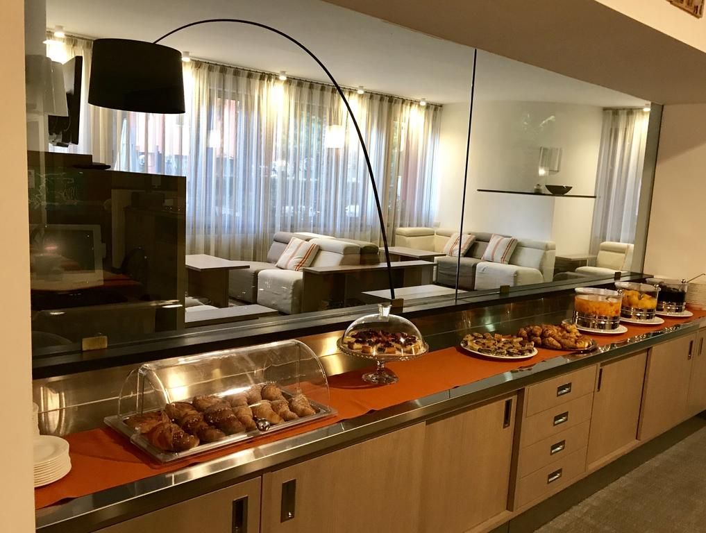 A hotel room with a breakfast bar, a sofa, and a large mirror.