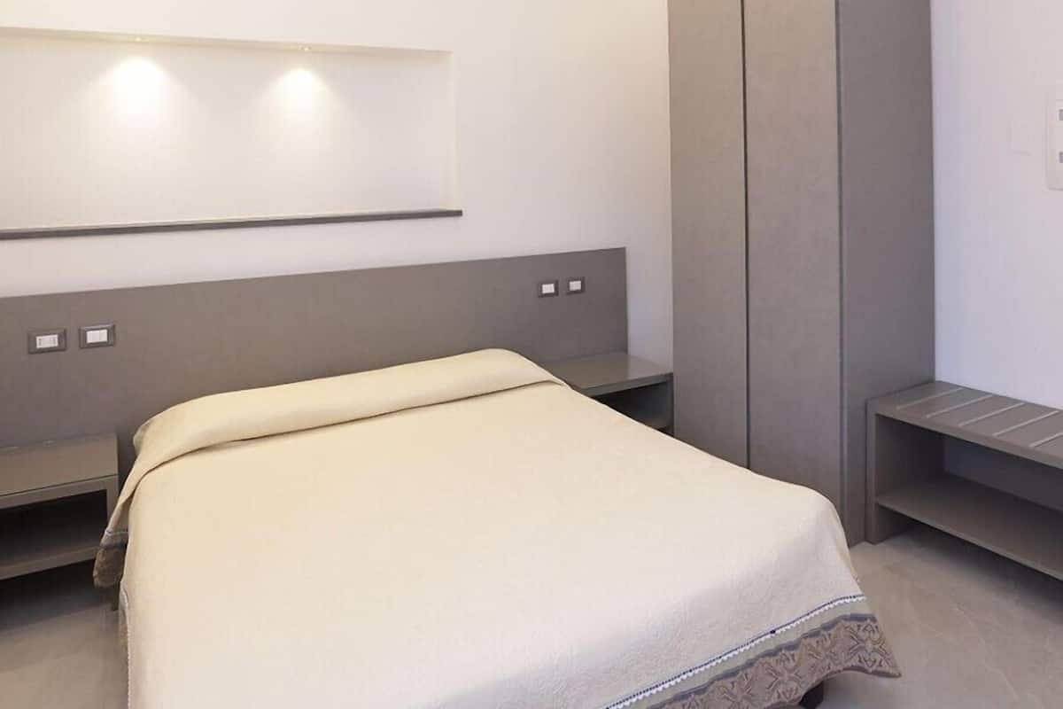 Een moderne hotelkamer met een bed, een kledingkast en een bank.