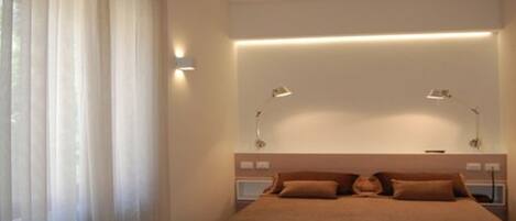 A modern hotel room with a neatly made bed, bedside tables, and a desk.