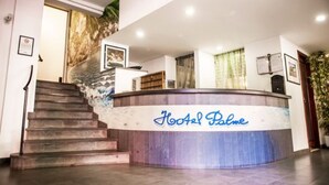 A hotel reception desk with a staircase leading up to it. - Hotel Palme (Monterosso al Mare)