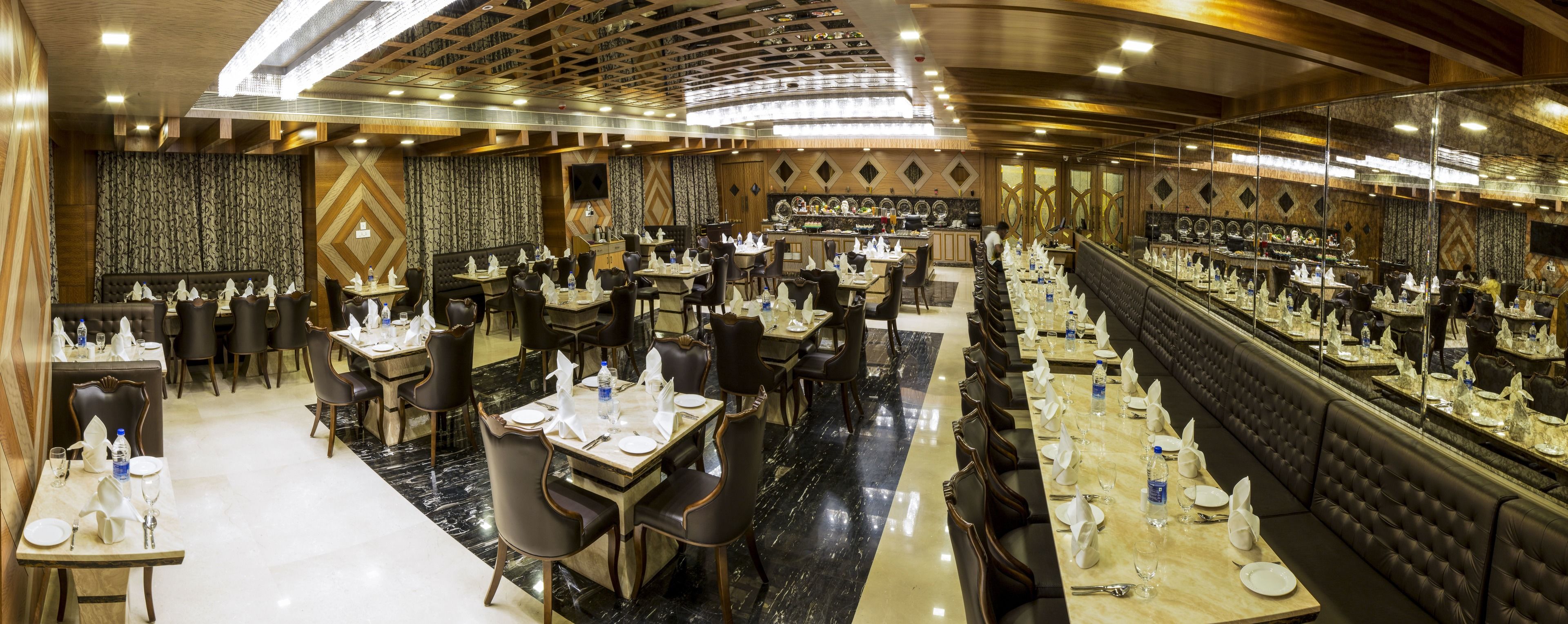 Un ristorante spazioso con diverse zone pranzo, tra cui un lungo tavolo comune e cabine individuali.