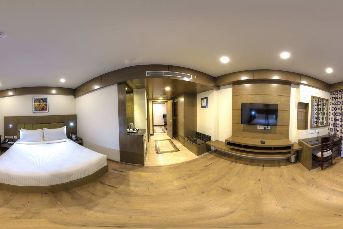 Ett rymligt hotellrum med en stor säng, ett skrivbord, en TV och en sittgrupp.