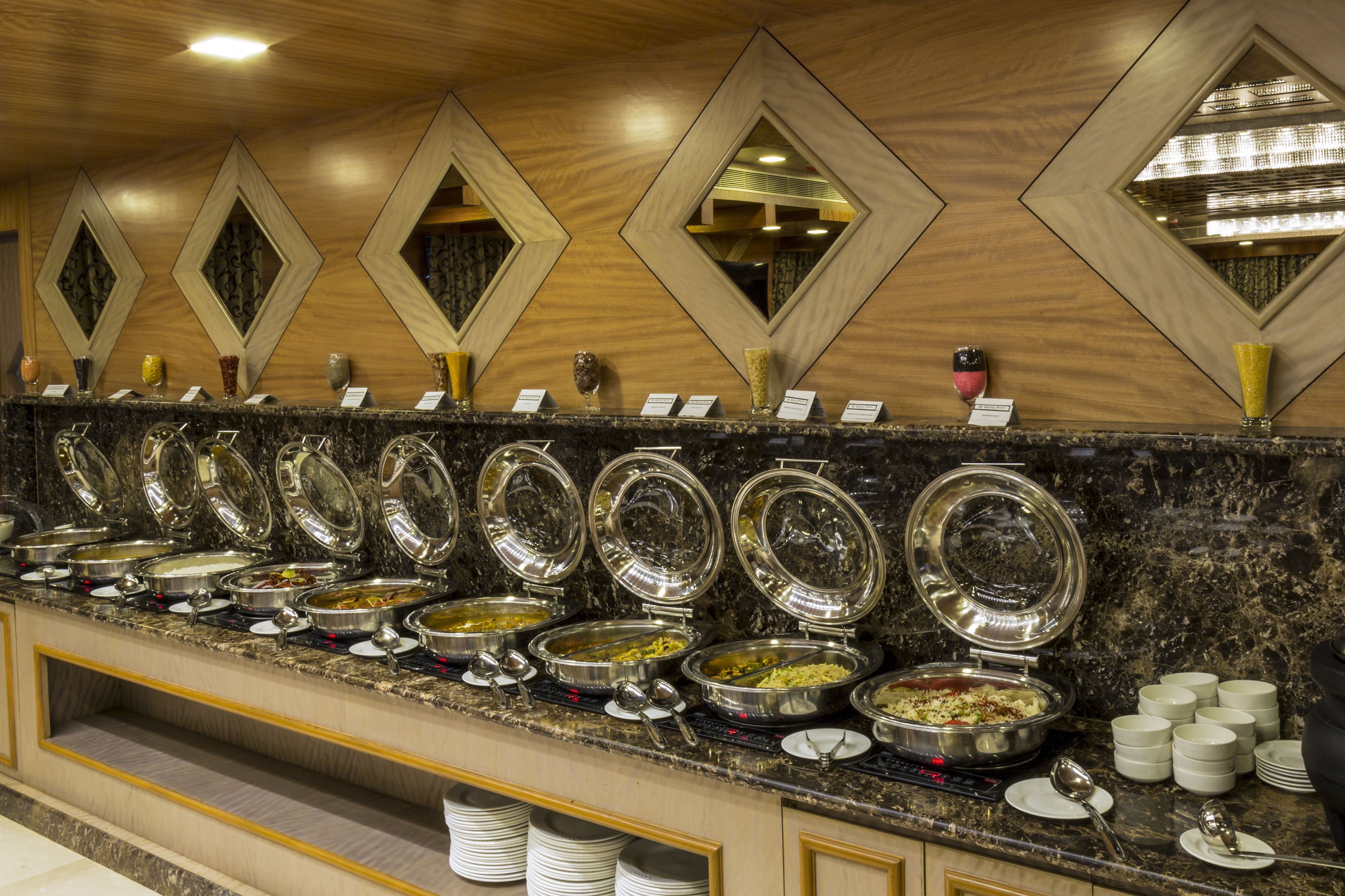 Buffet com várias estações de serviço, cada uma com uma variedade de pratos e utensílios.