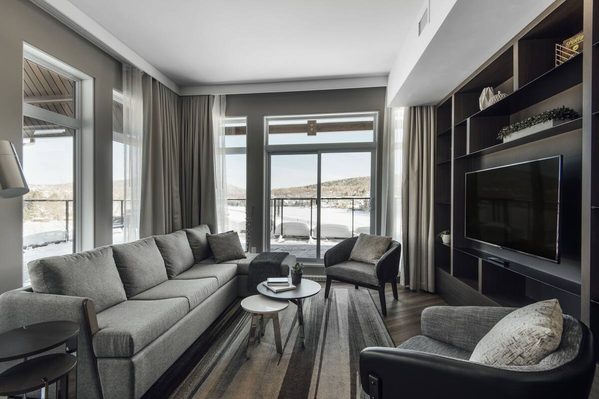 Un salon moderne avec un canapé, des fauteuils, une table basse et un téléviseur à écran plat.