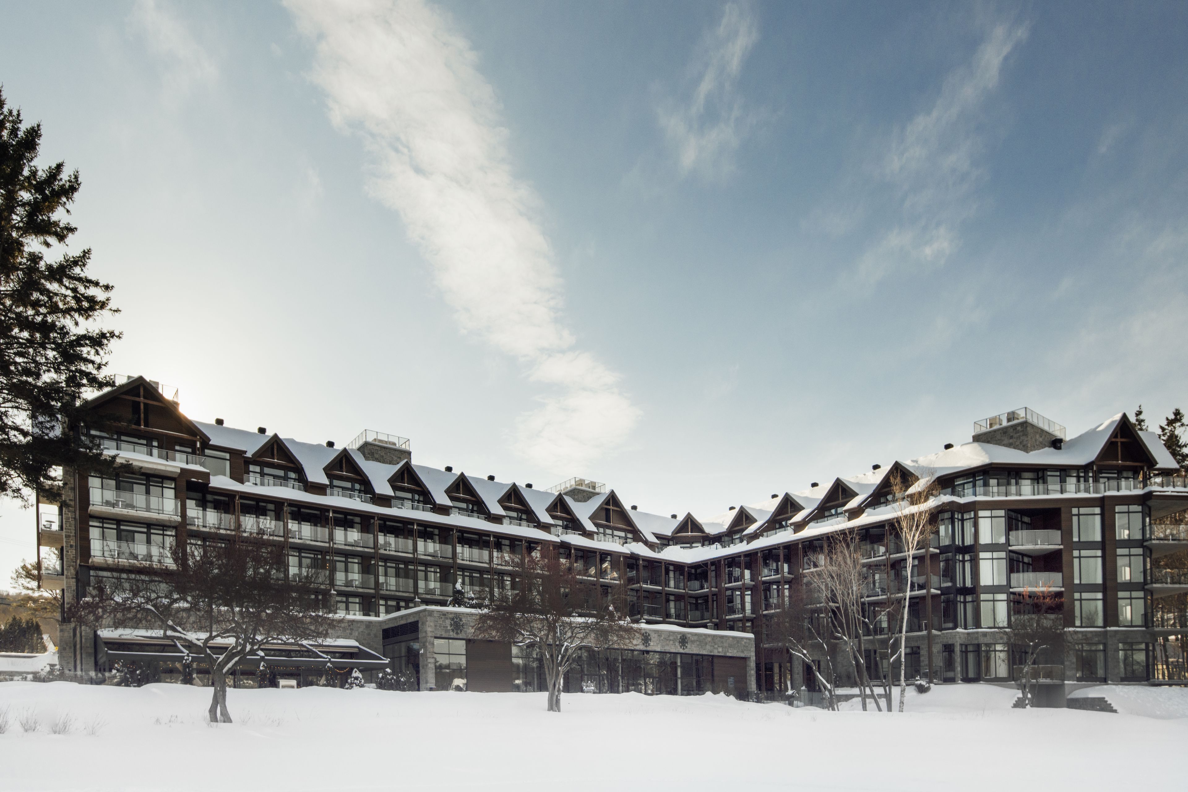 A modern multi-story building with a symmetrical facade, large windows, and a snow-covered roof.