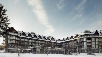 A modern multi-story building with a symmetrical facade, large windows, and a snow-covered roof.