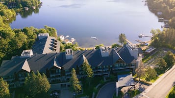 An aerial view of a hotel with multiple buildings, a parking lot, and a lake with boats.